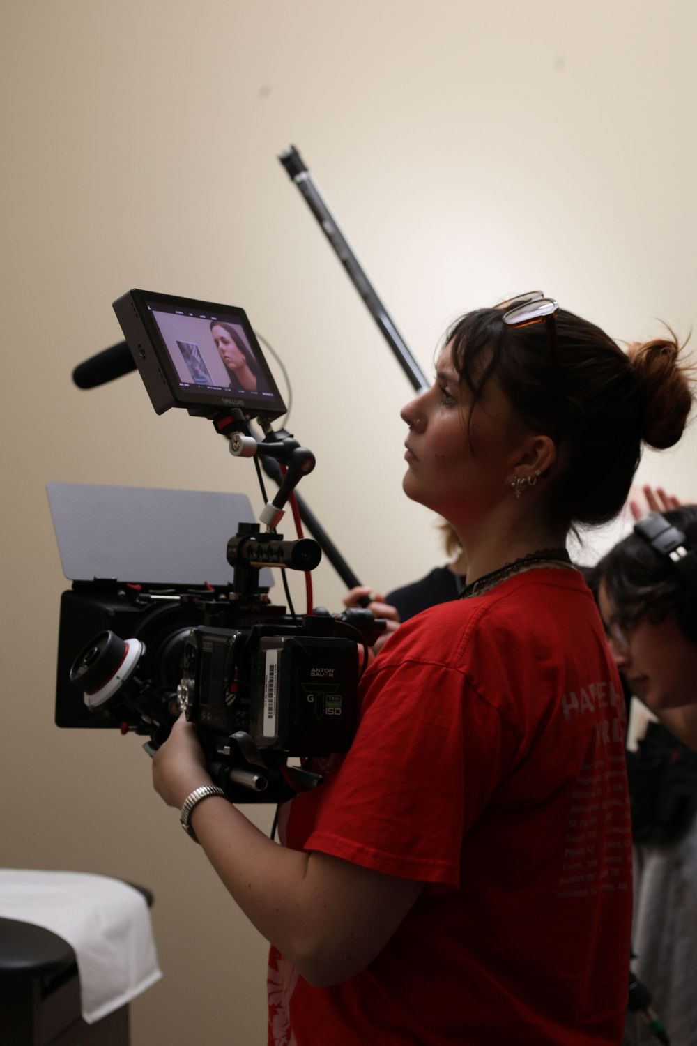 Camera operator in red t-shirt films with professional video equipment from multiple angles.