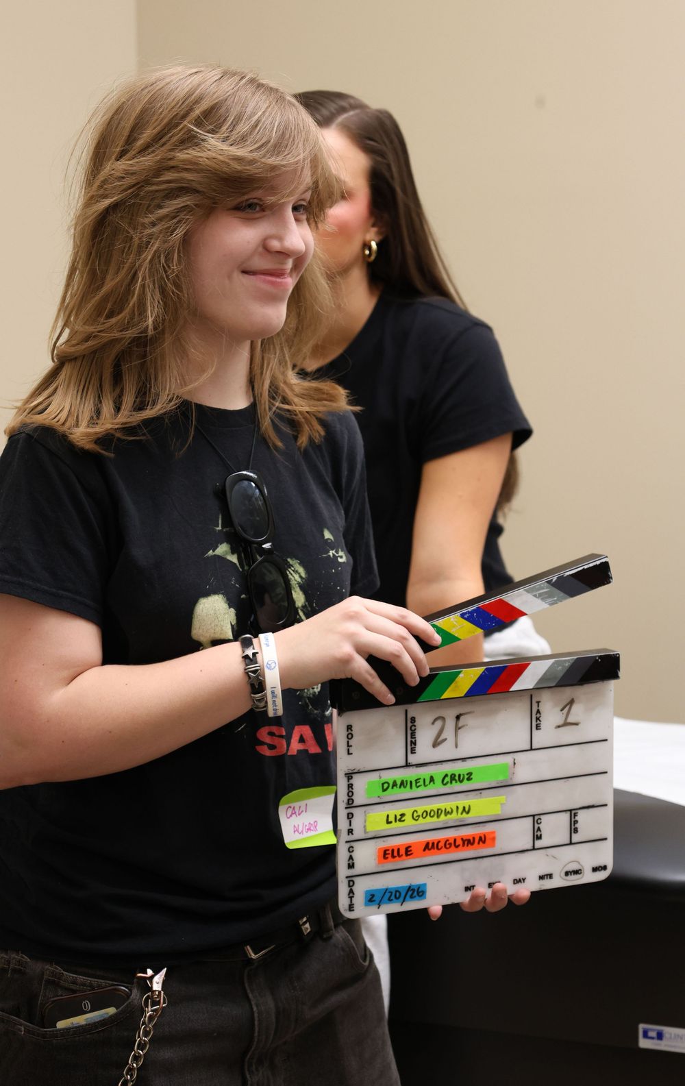 Person in black t-shirt holding and displaying a film production clapperboard in multiple shots.