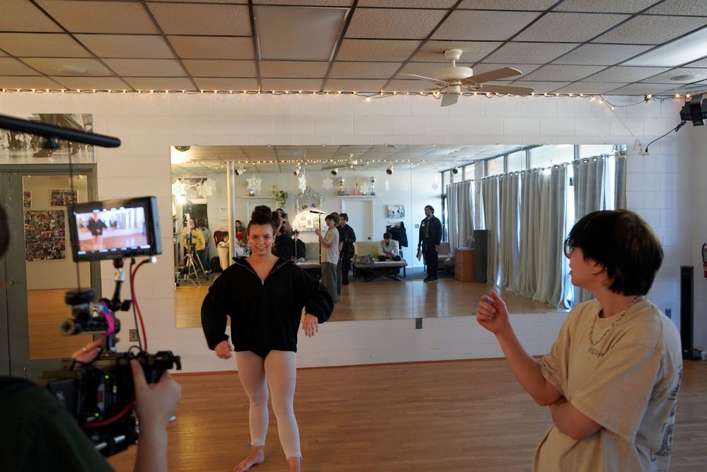 Interior view of a modern gallery or museum space with white walls and hardwood floors showing multiple displays.