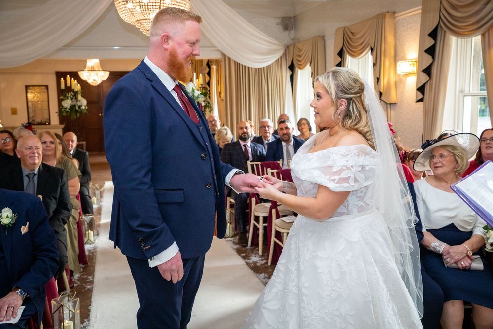Bride and groom exchanging rings during intimate wedding ceremony before smiling seated guests.
