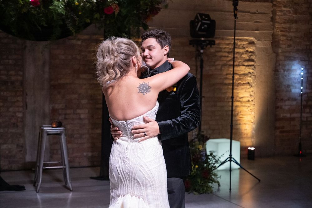A couple shares an intimate dance moment in a rustic brick-walled venue with warm lighting.
