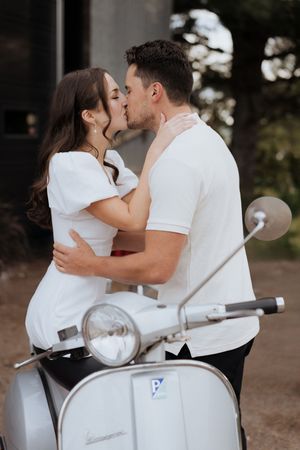 bride and groom kiss on vintage vespa in classic vintage elopement in Moncton wedding photographer packages near me, intimate micro-wedding