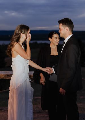 Bride and groom hold hands during wedding ceremony in surprise wedding outdoor night time elopement in Moncton wedding photography packages