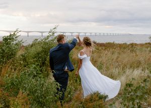 couple dance at sunset in front of the confederation bridge, ocean view coastal elopement photography in New Brunswick, PEI wedding photos