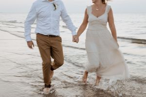 Couple run hand in hand at sunset during beach wedding elopement in Halifax Nova Scotia, adventure elopement packages, outdoor wedding in NS
