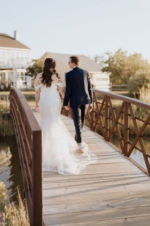 Bride and groom walk hand in hand across a bridge during intimate elopement in Shediac New Brunswick, travel destination vacation photos