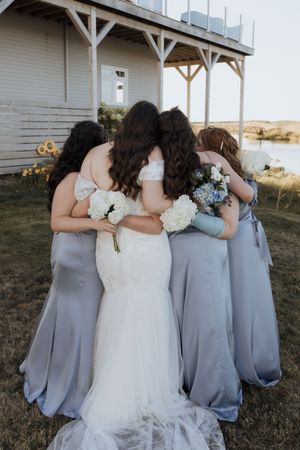 Bride and bridesmaids hug during candid moment, Cap Pele wedding photography, intimate elopement photography Moncton New Brunswick