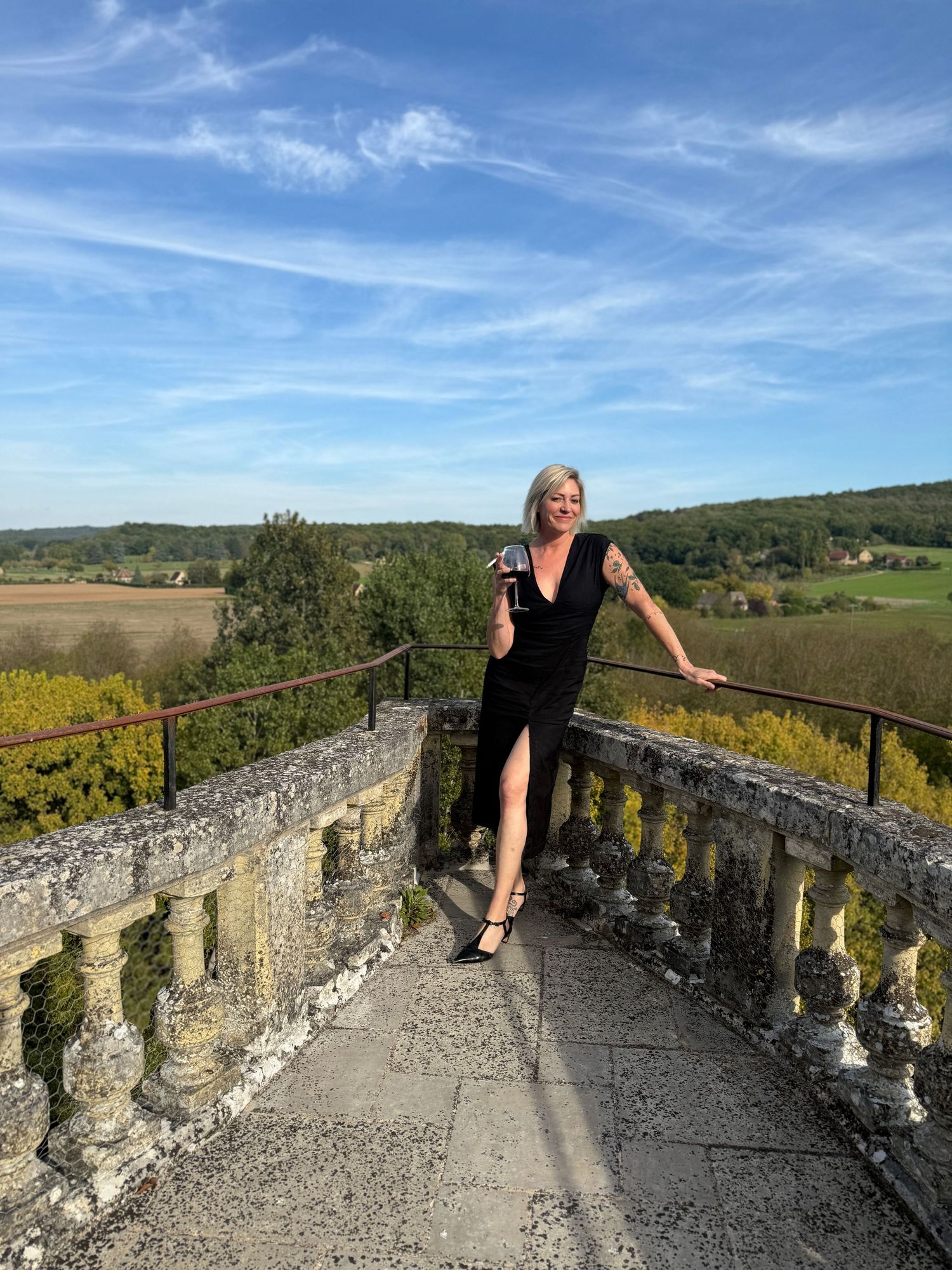A woman stands on a stone bridge, enjoying the scenic countryside view.