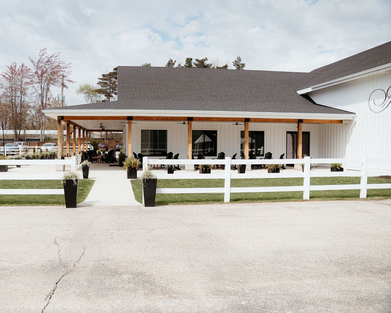 The Ivy House Wedding Venue. Elegant White ranch-style building with covered porch and white fence in front.