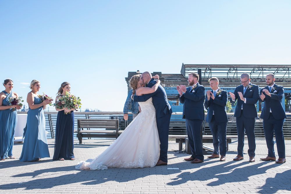 Wedding party poses for formal photos on a sunny day with ocean views in the background.