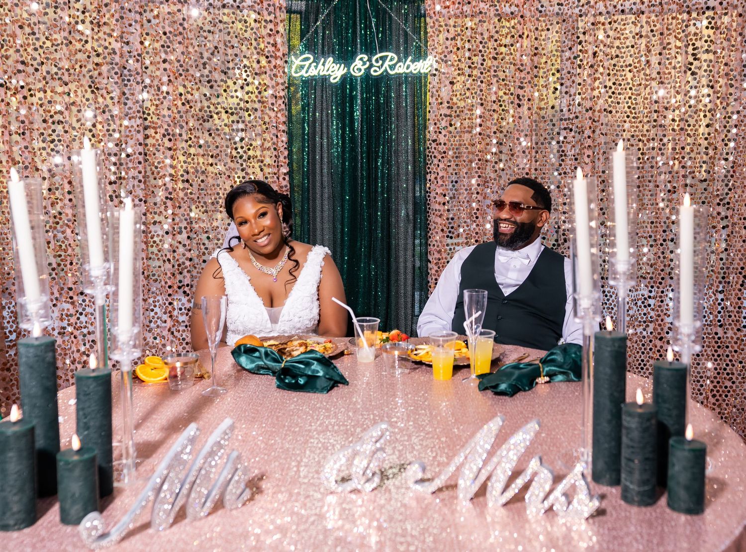 A couple sits at a wedding reception table decorated with sparkling lights and glowing candles.