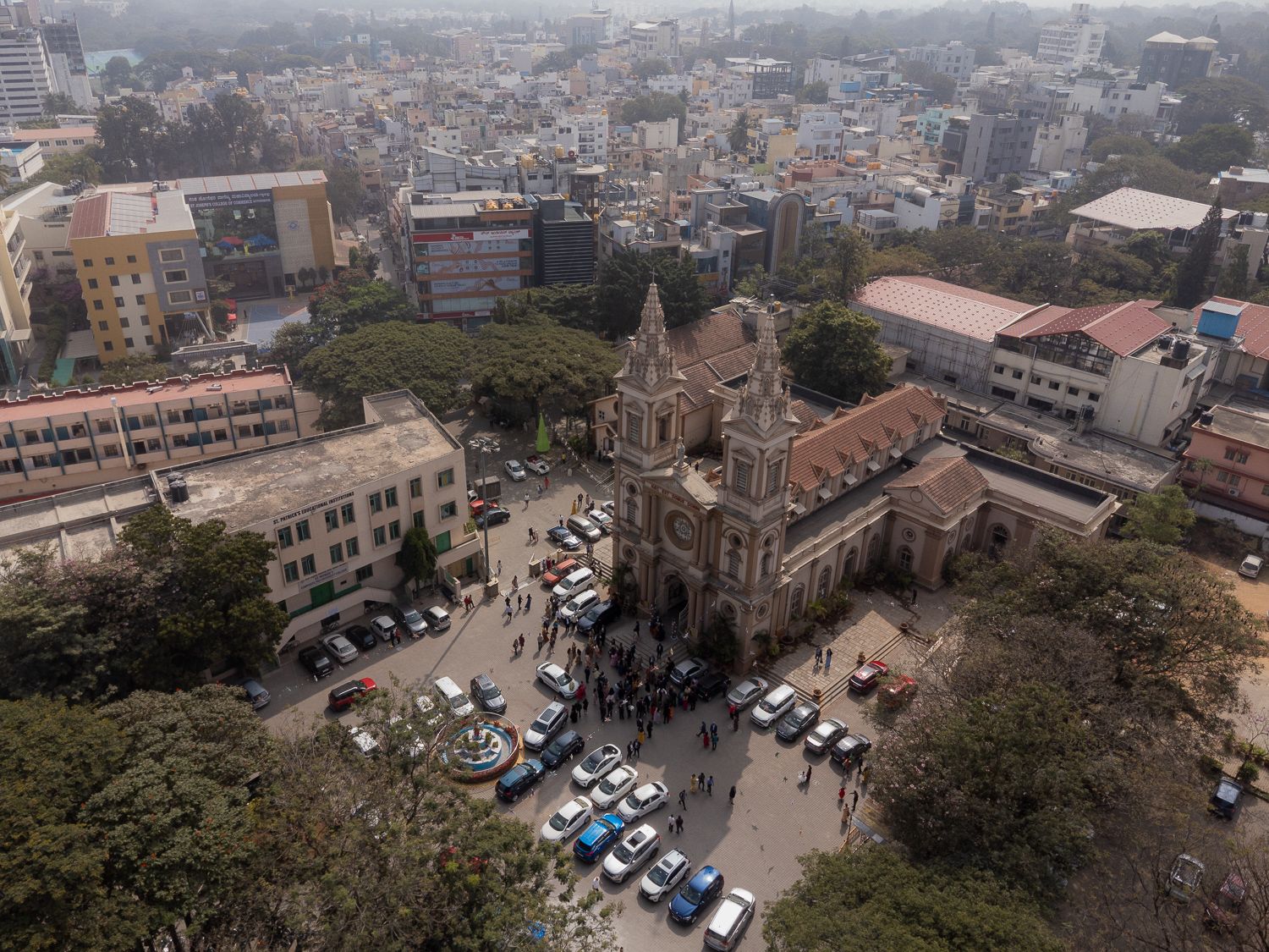 Aerial panoramic view of a dense urban cityscape with buildings and parked cars visible from above.