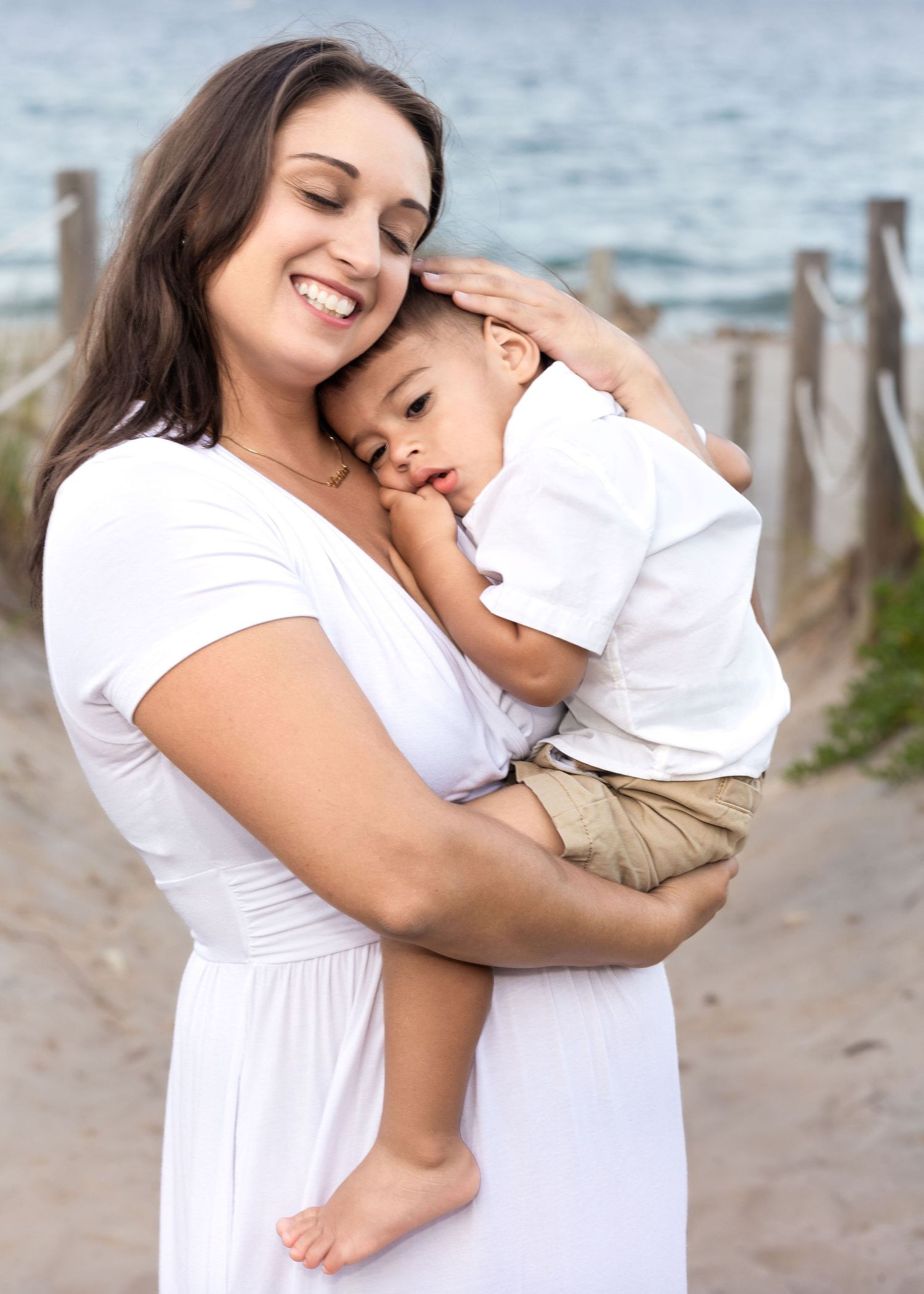 A mother and young child share tender embraces in a series of loving poses on a beach at sunset.
