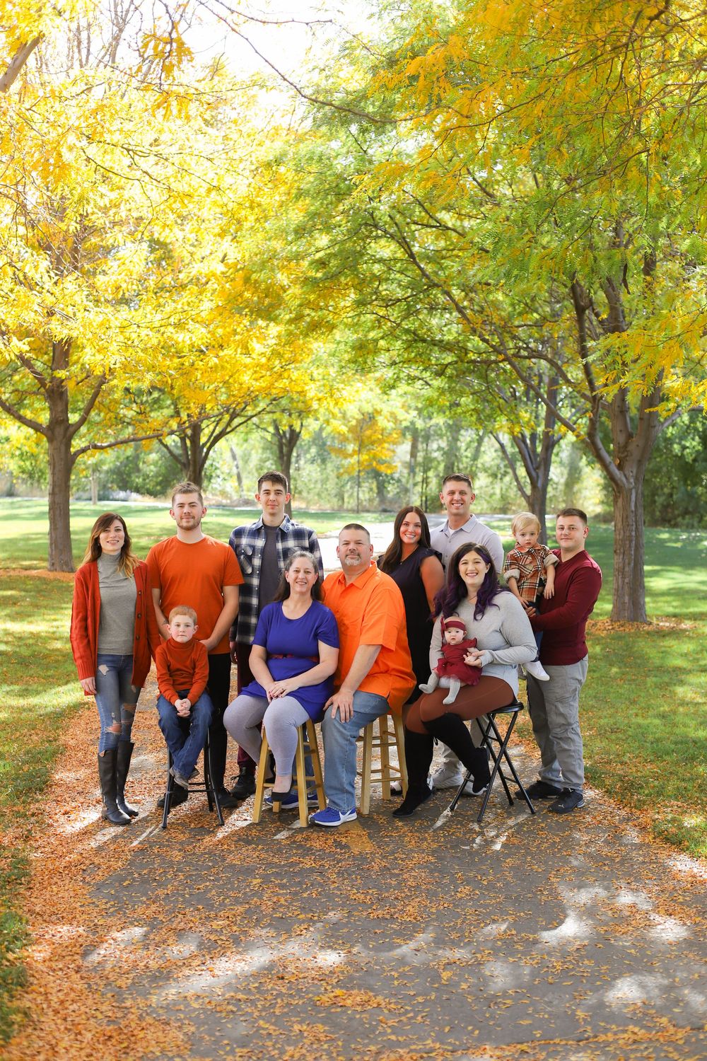A group poses together on an autumn path surrounded by yellow and green trees in a park setting.