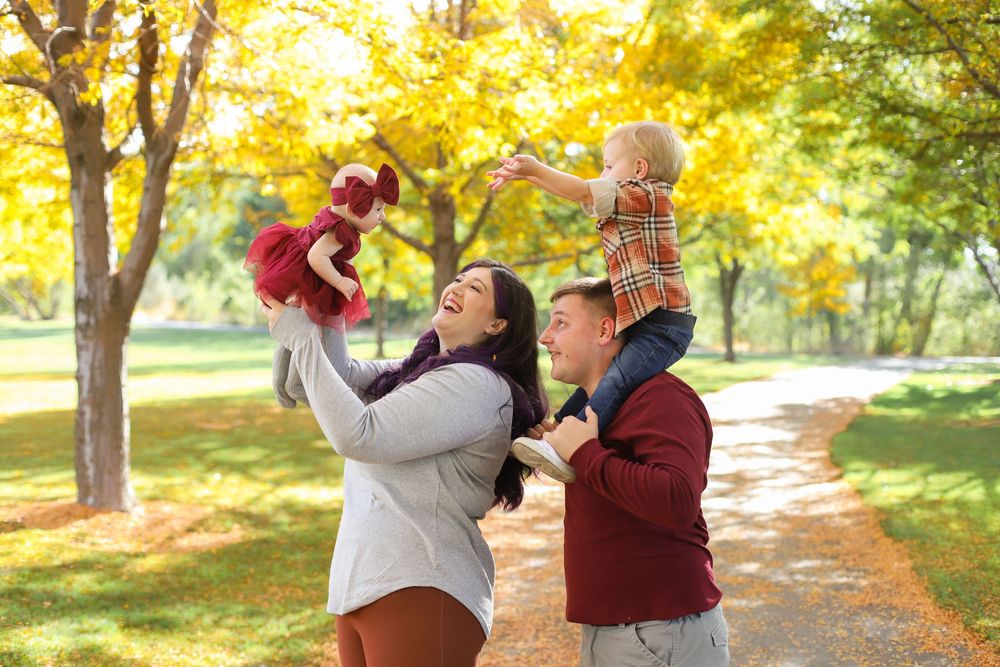 A joyful autumn photoshoot in a park with golden foliage and sunlight streaming through the trees.