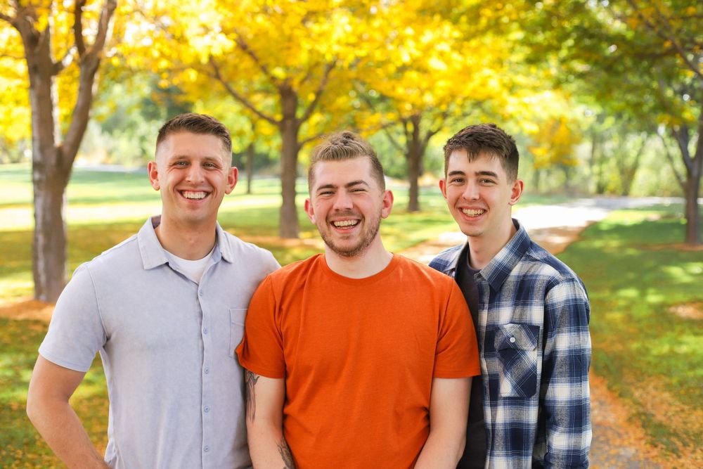 A group poses together on a fall day with colorful autumn leaves and trees in the background.