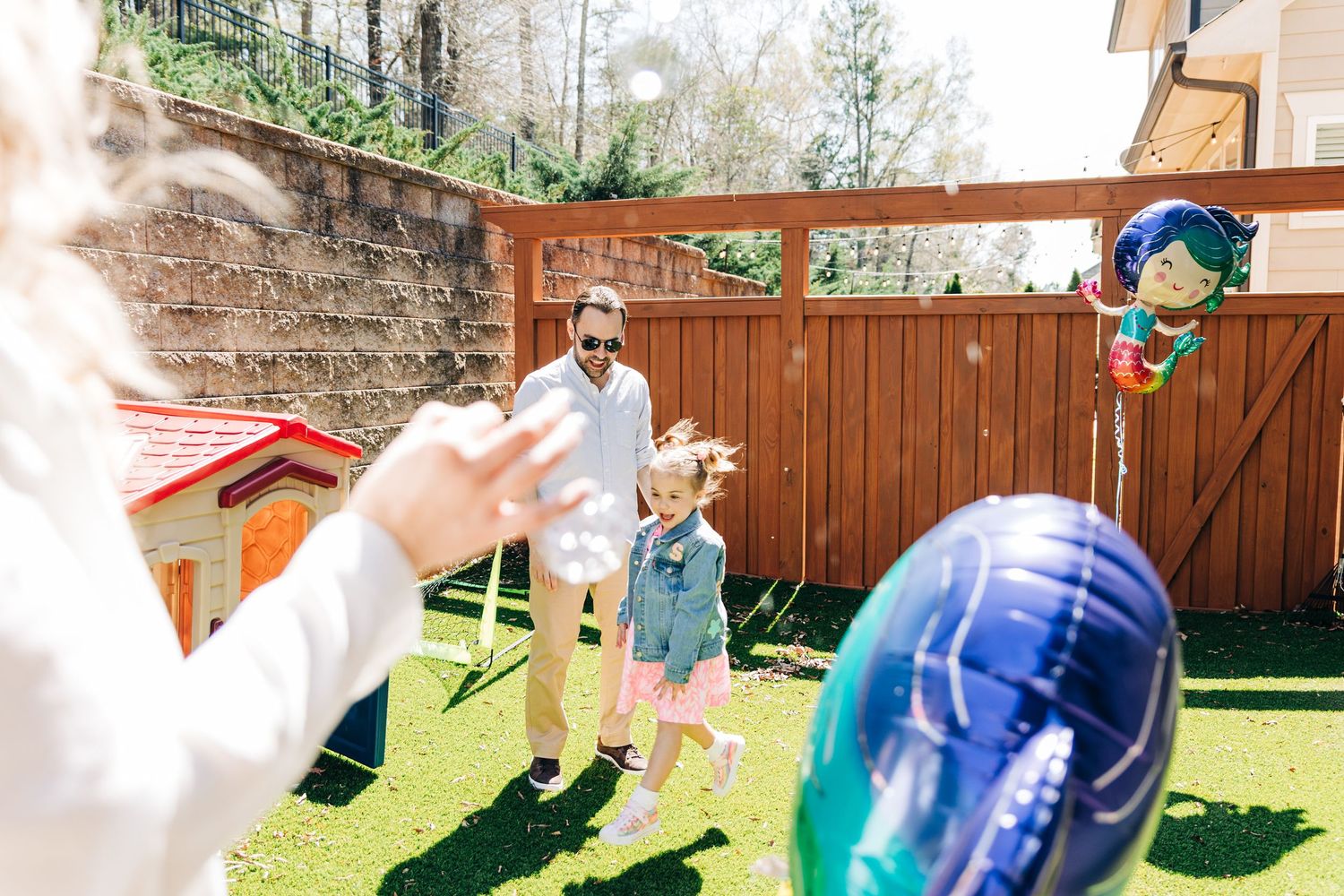 An outdoor party activities with bubbles, games, and decorations in a backyard setting with little girl  jumping after bubbles in Charlotte