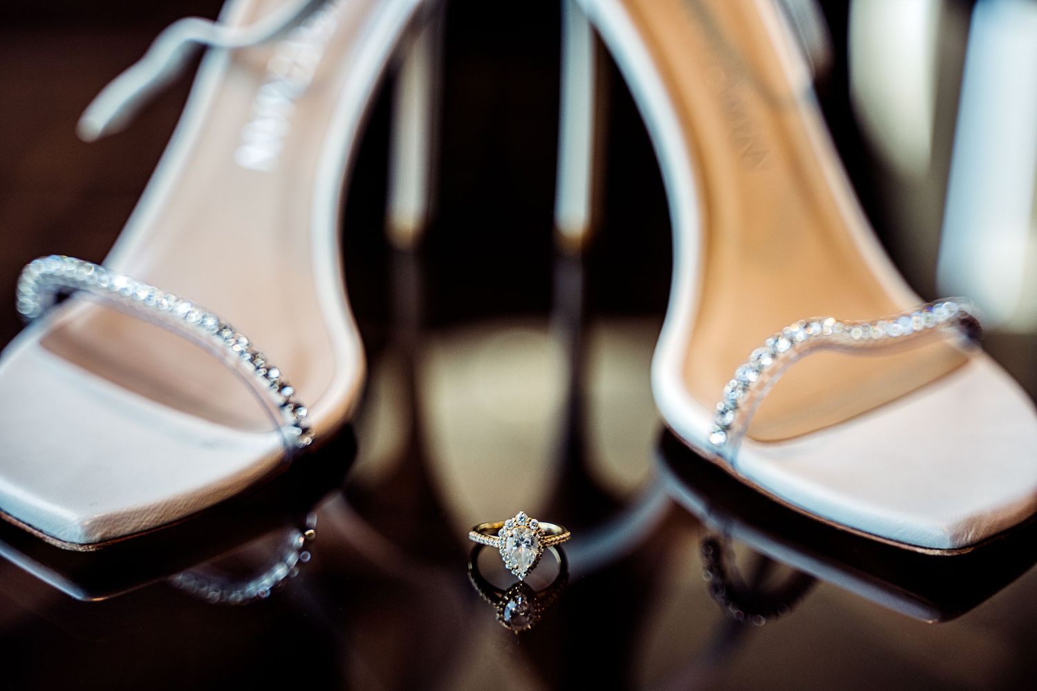 A close-up of elegant silver rhinestone bridal shoes displayed in multiple angles on a dark surface.