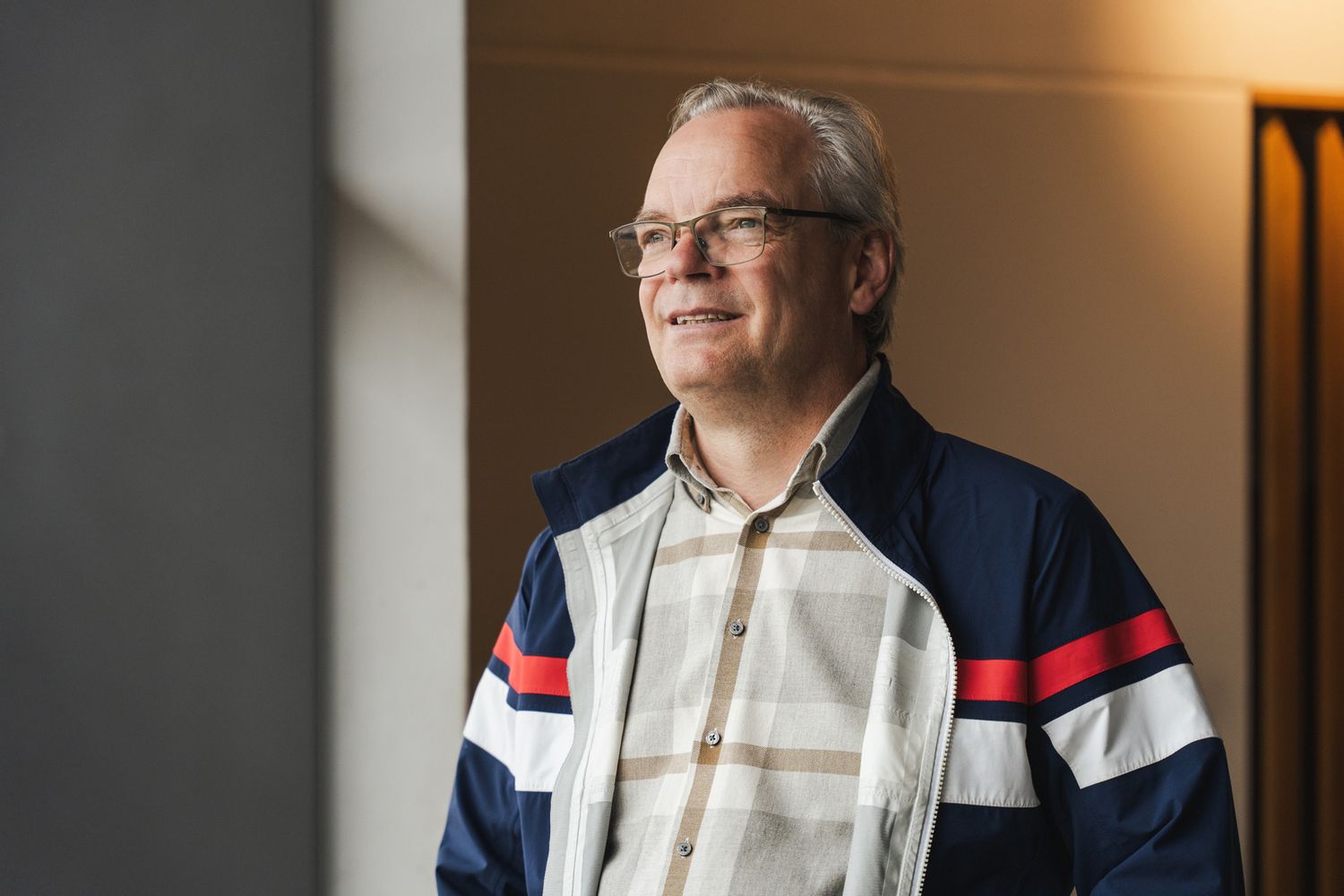 Porträtt av manlig expert med glasögon som tittar ut genom ett fönster.