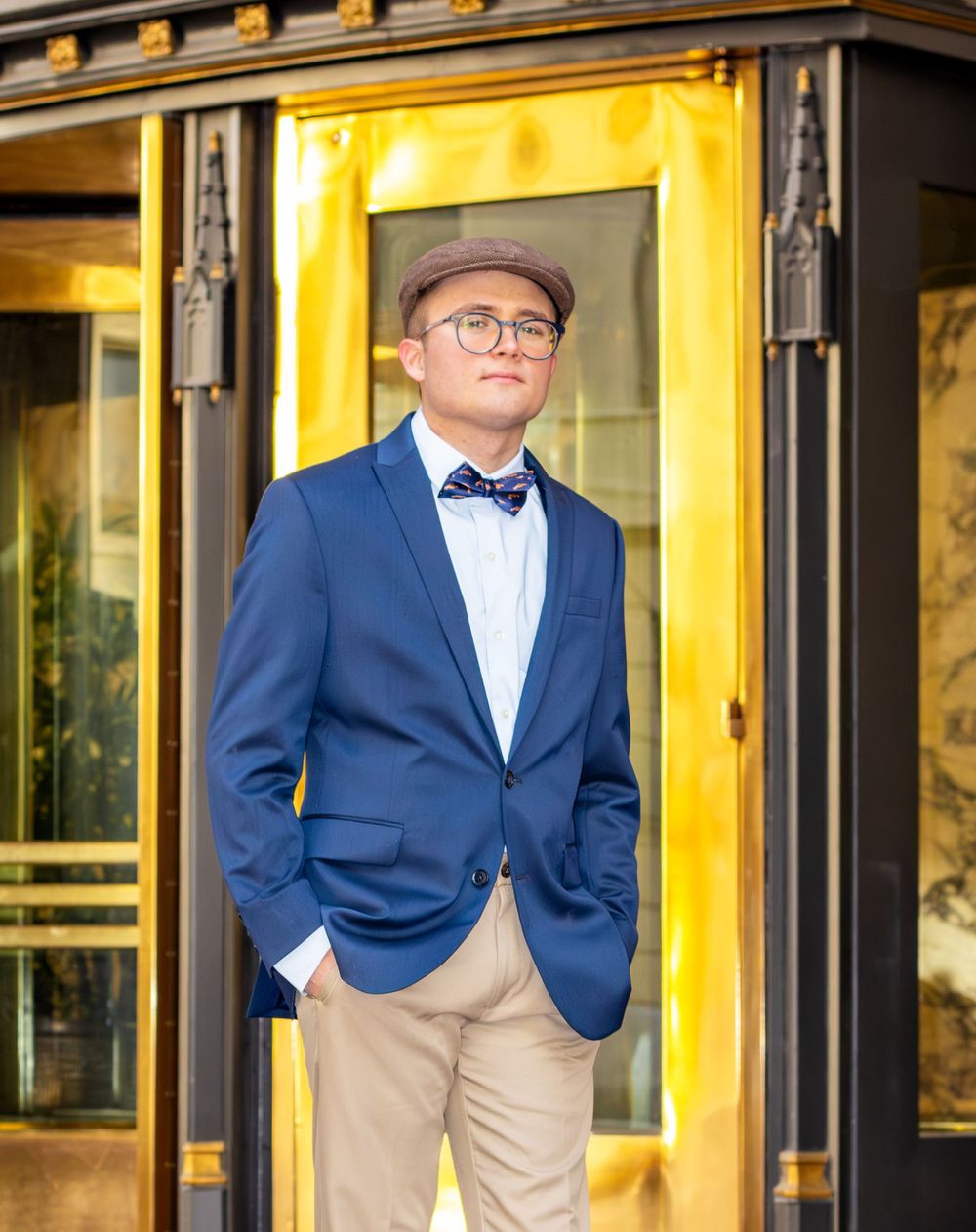 A figure in a navy blazer and khaki pants poses against a yellow-lit building exterior in four similar shots.