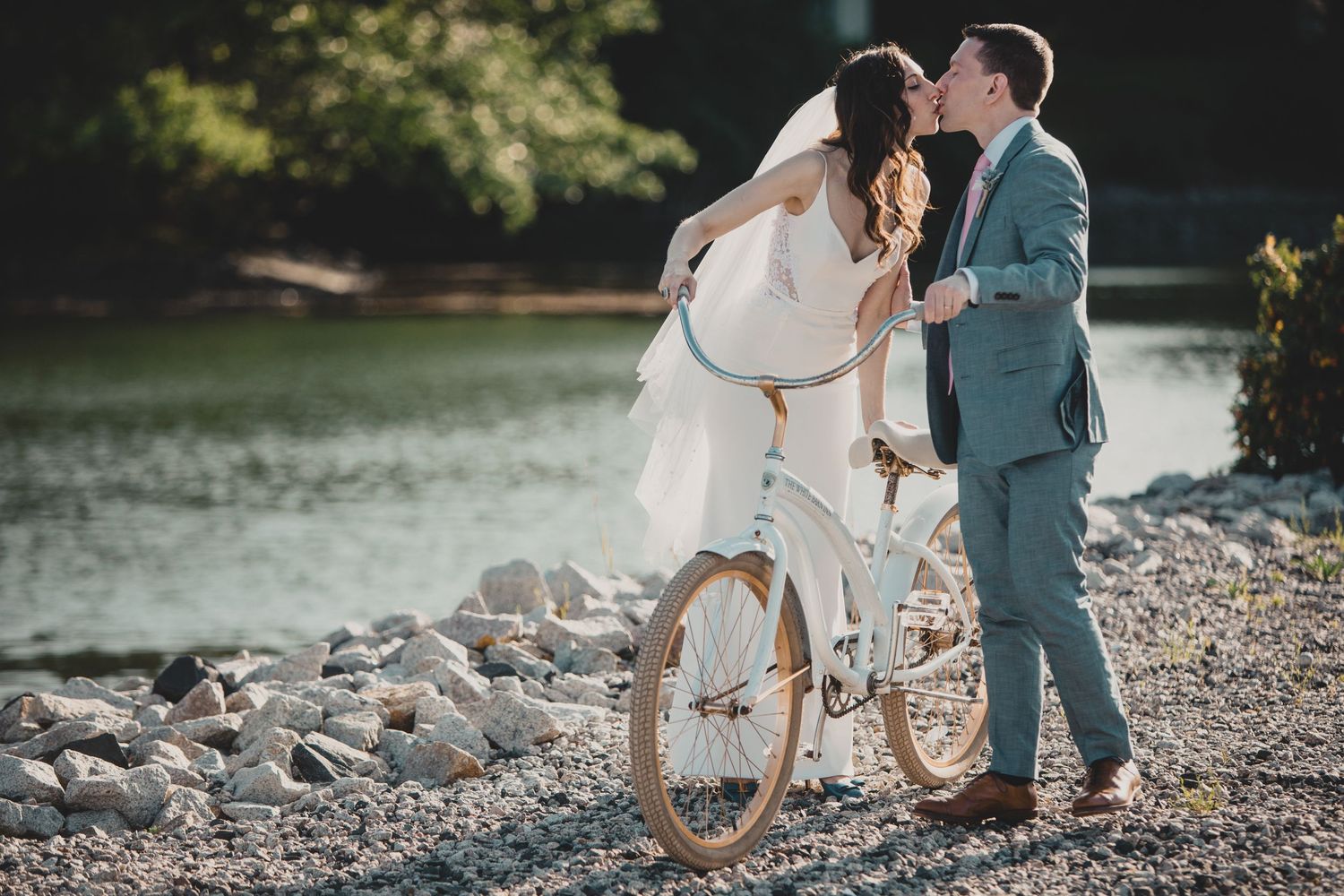 Wedding party walks along a scenic wooden dock at a marina with boats and water in the background.