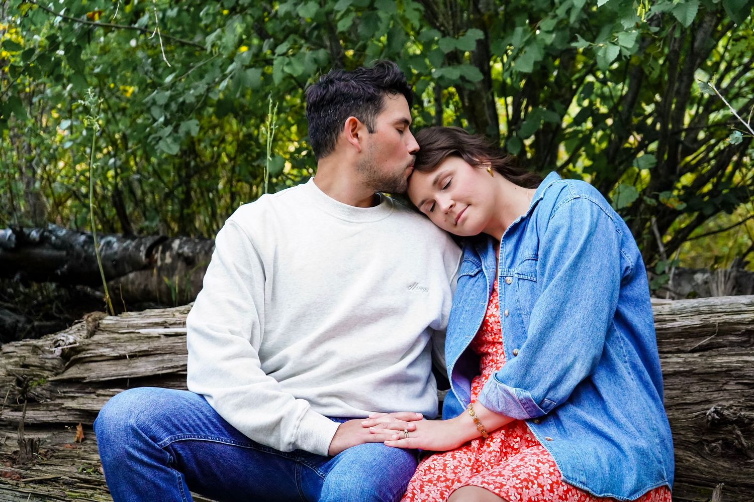 Couple kissing romantically by a scenic mountain lake on a sunny day.