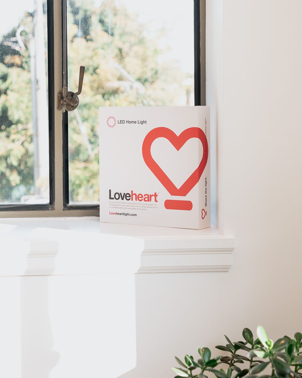 Loveheart LED home light product box with red heart logo displayed on a white windowsill with natural light.