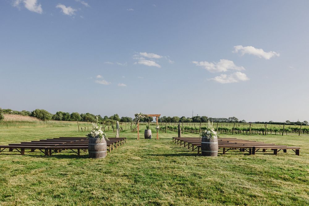Panoramic view of a horse farm with wooden fences stretching across green pastures under a blue summer sky.