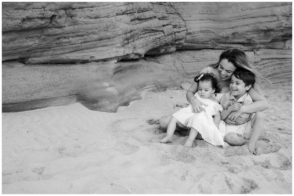 A series of black and white photos showing people resting and relaxing on a sandy beach against rocky cliffs.