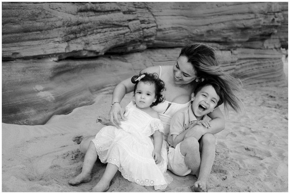 A mother and young child lying on a rock formation in black and white photography.