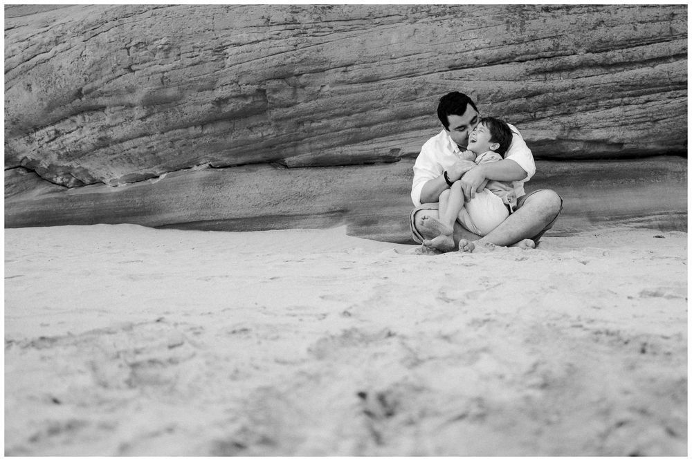 A sequence of black and white photographs shows two people sitting on rocks at a beach in various poses.