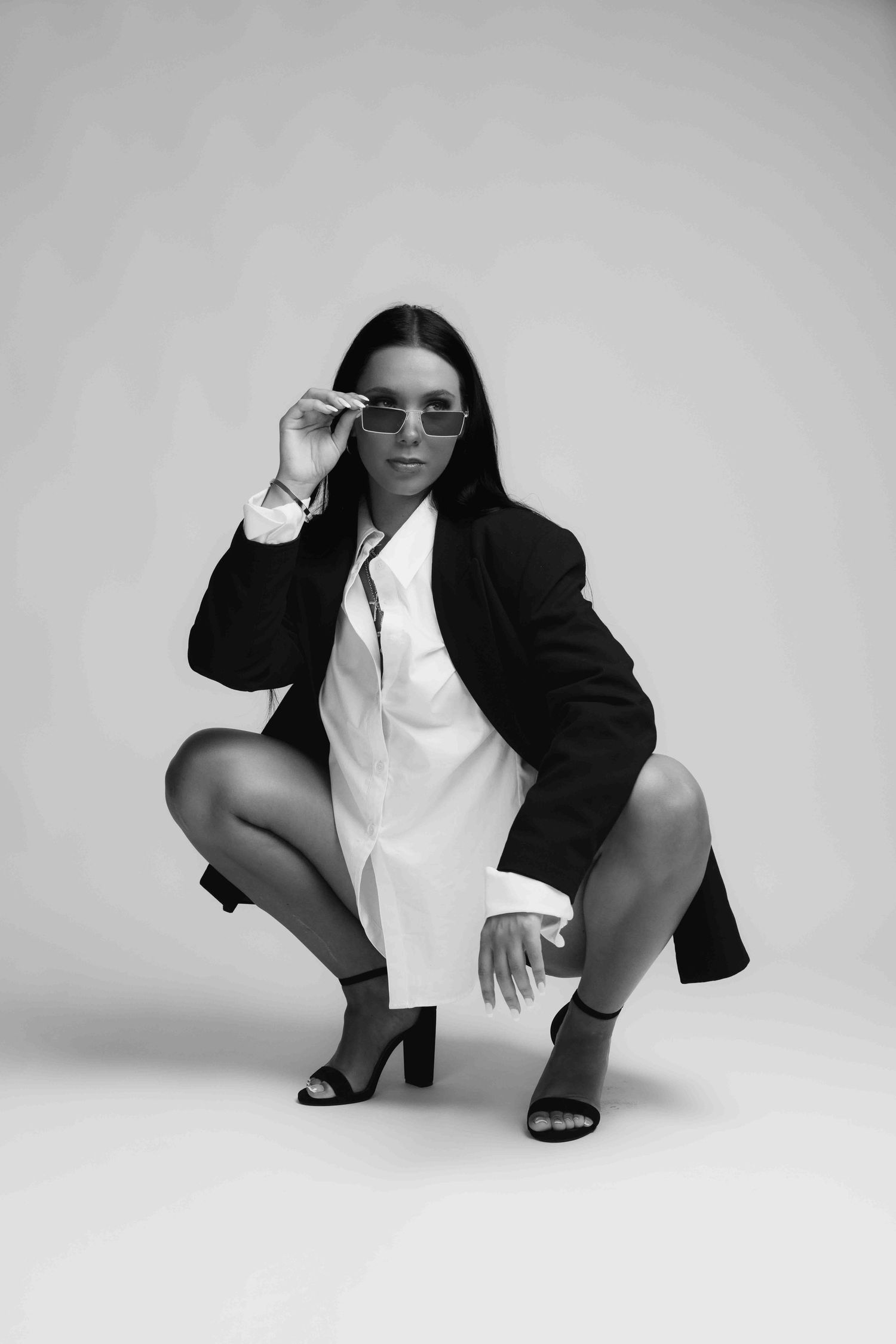 Professional fashion photo series showing model in black blazer and white shirt striking dynamic crouching poses.