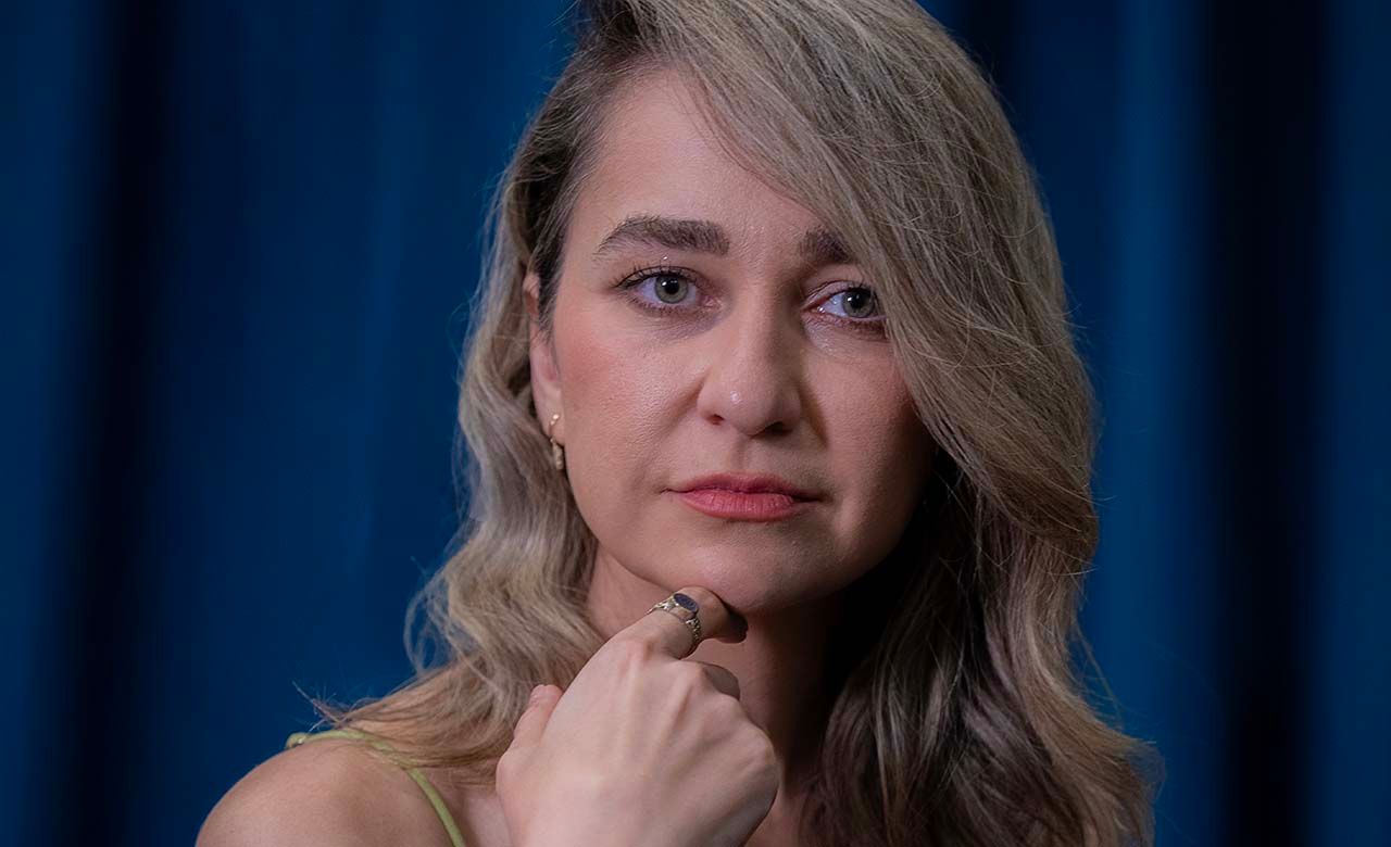 Dramatic portrait with moody lighting against dark blue background.