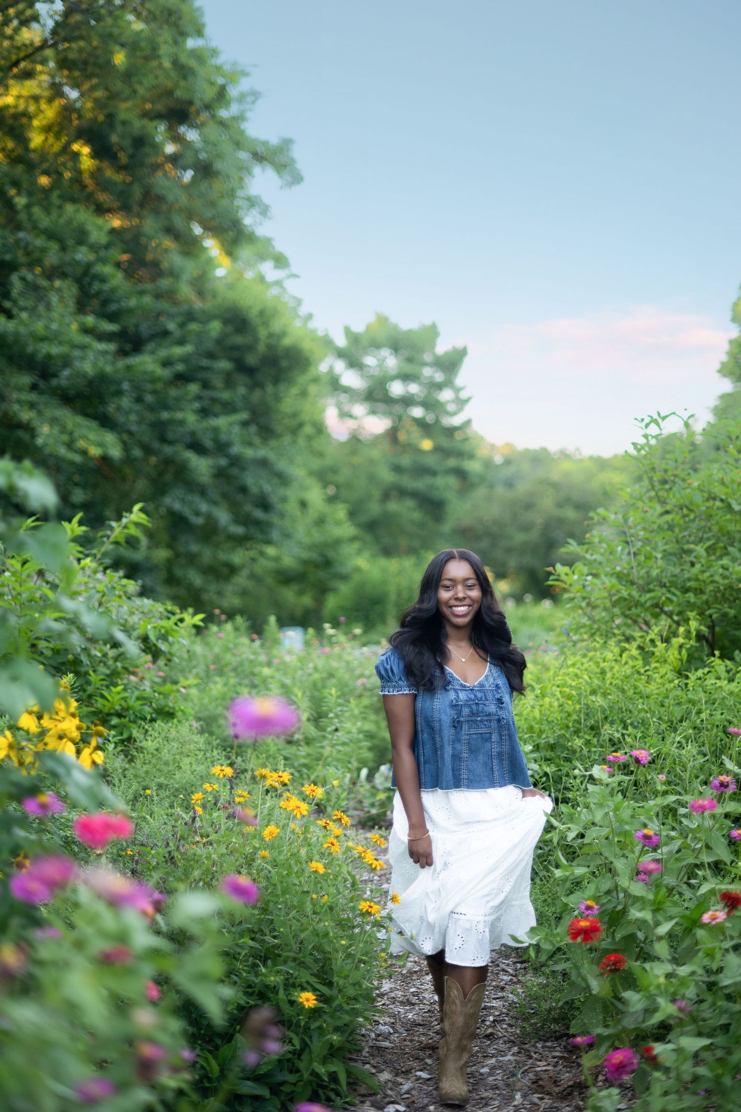 A person walks through a vibrant garden path filled with colorful summer wildflowers and greenery.
