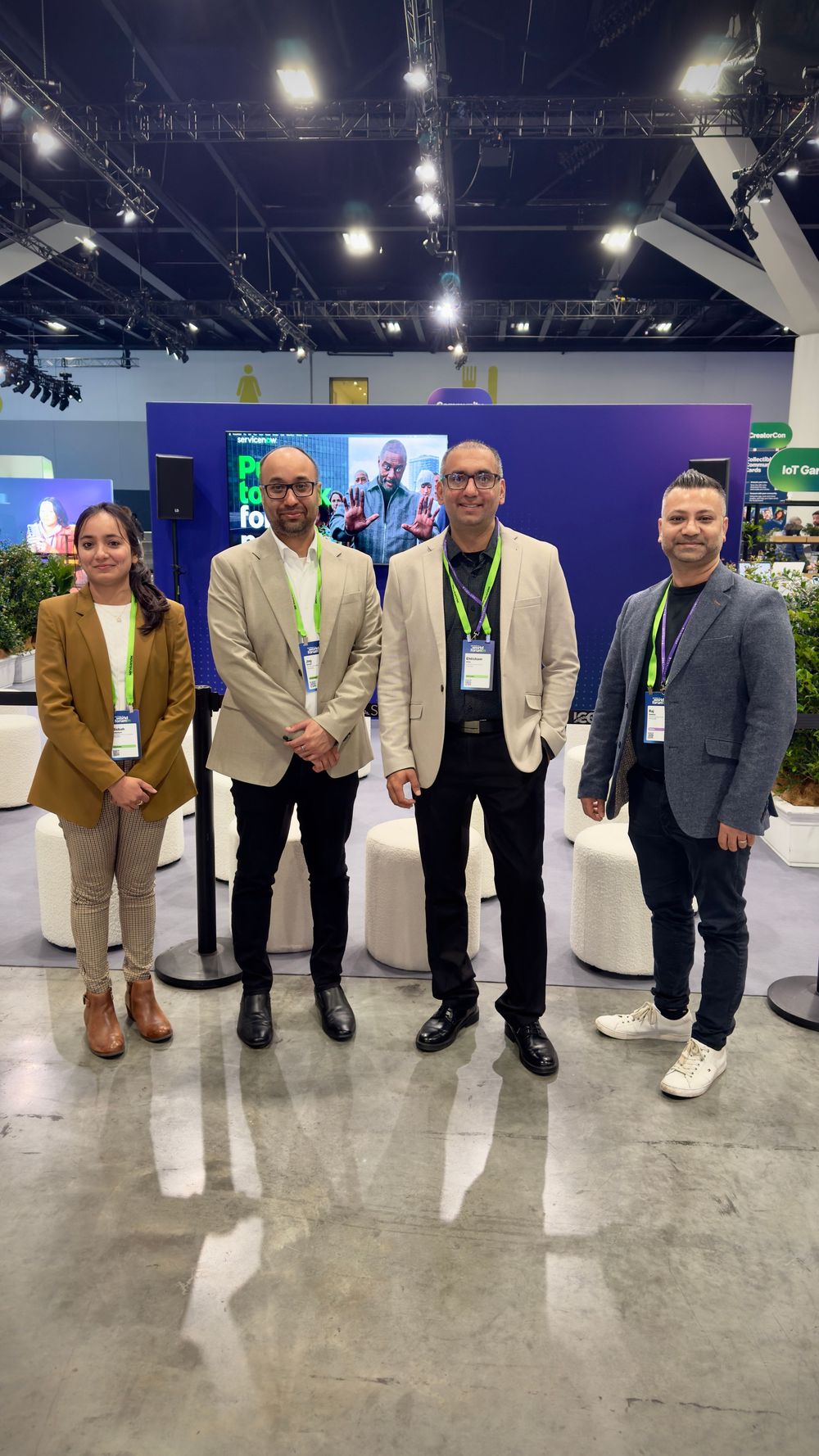 Four professionals in business attire posing together at a corporate tech conference expo.