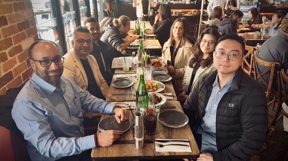 Small group of colleagues enjoying a business lunch at a cozy brick-walled restaurant.