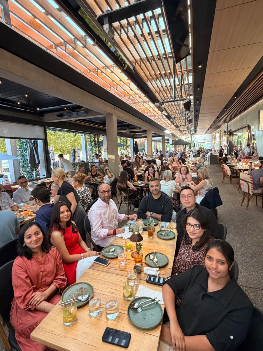 Large group of diverse professionals dining together at a busy modern restaurant with warm lighting.