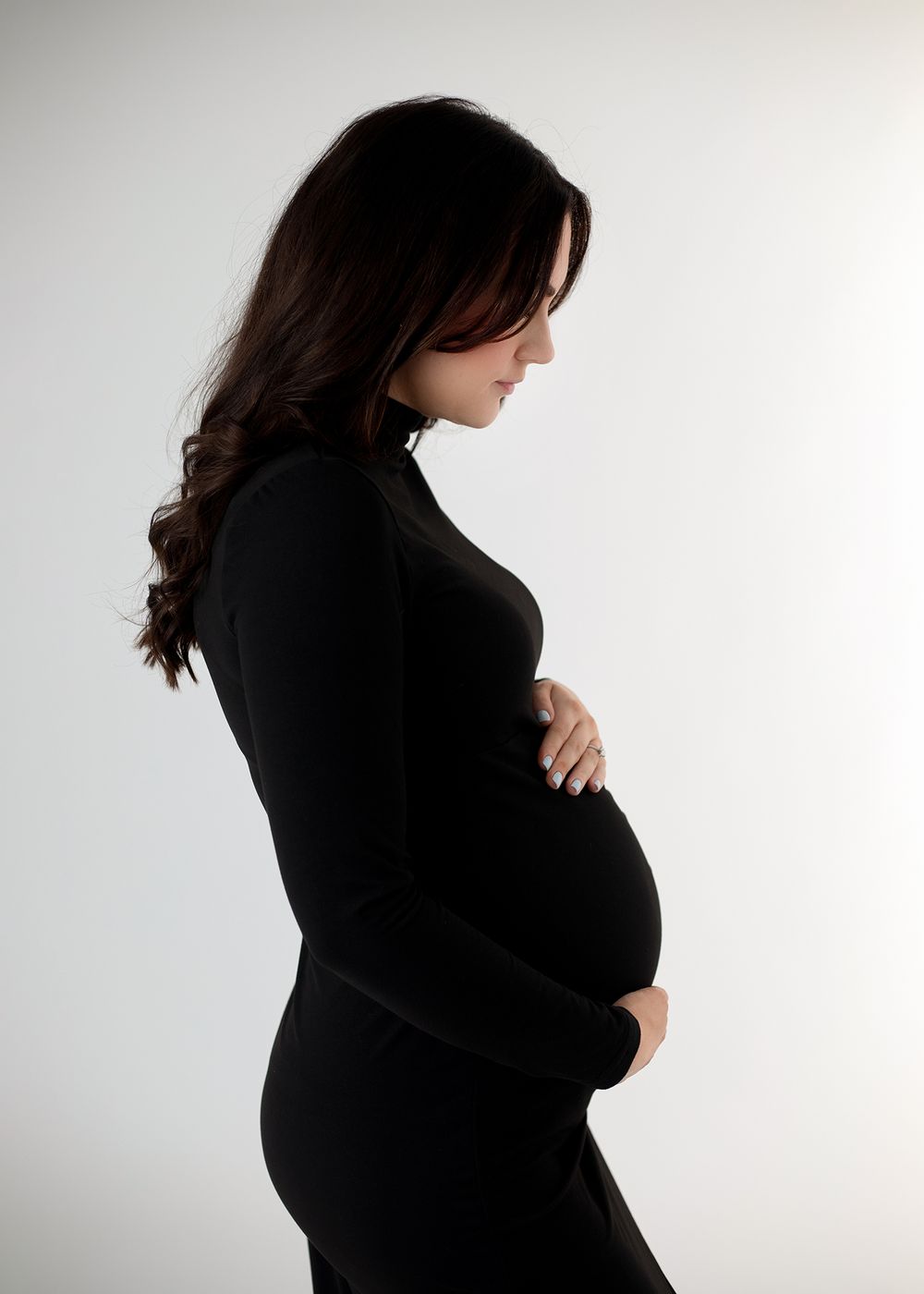 Side profile silhouette of an expectant mother in a black dress against a white background.