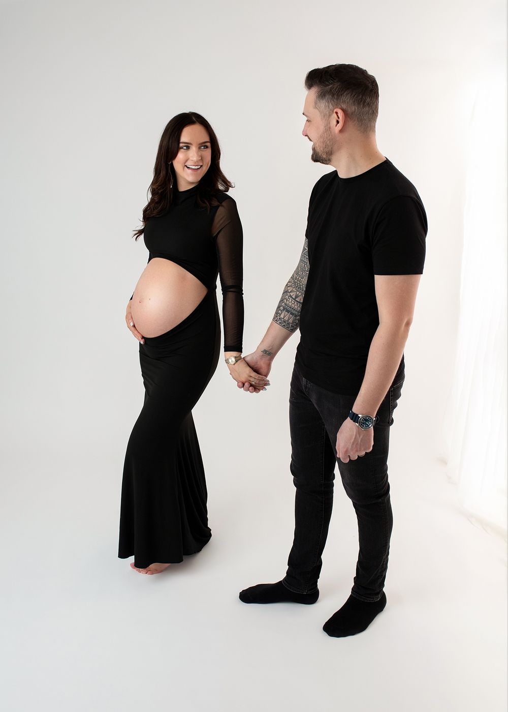 A series of black and white studio photos showing a couple in dark clothing posing together against a white backdrop.