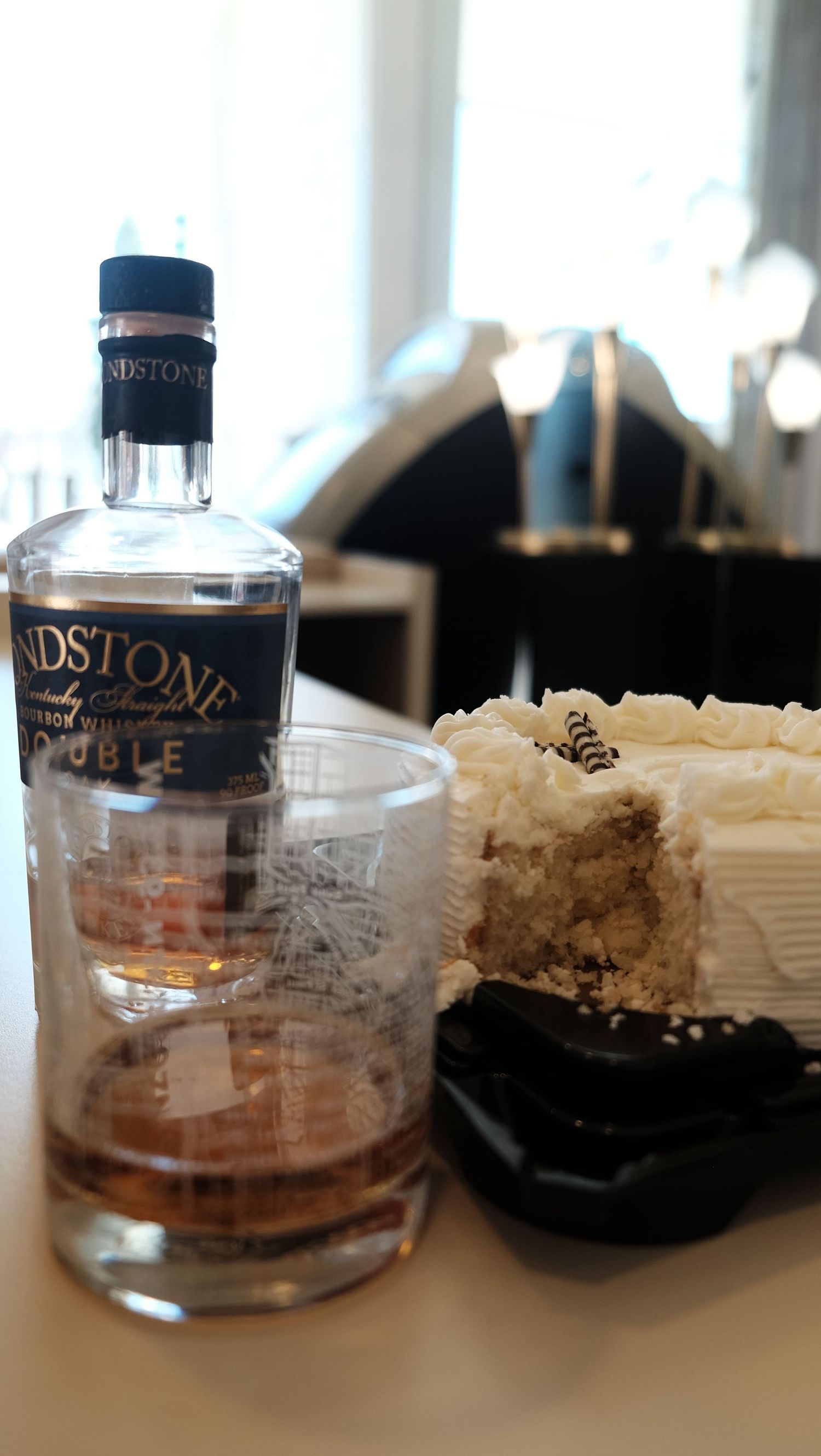 Bloodstone double Kentucky straight whiskey bottle with a glass and white frosted cake slice.