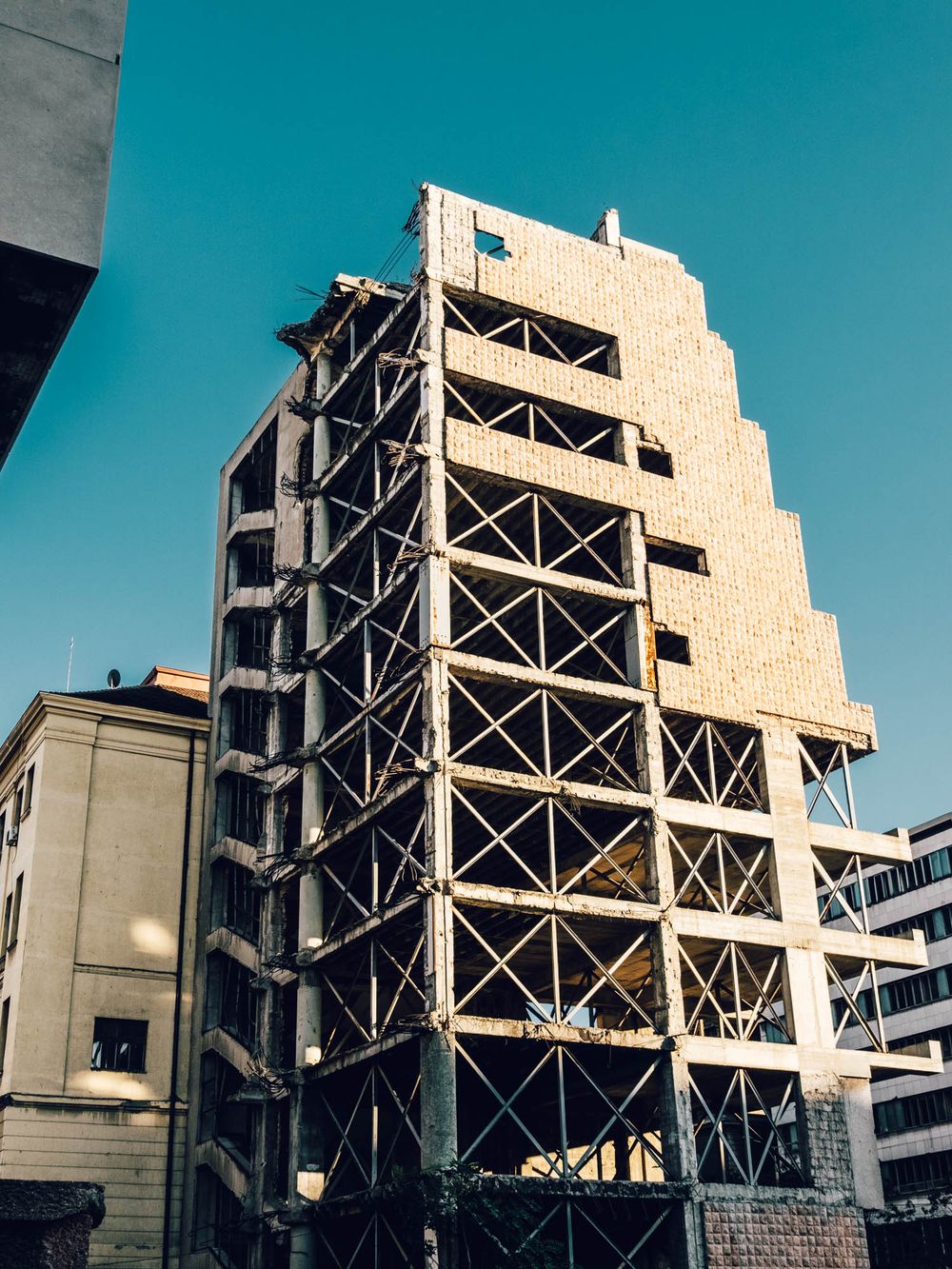 Urban building under construction with steel scaffolding against a clear blue sky in a city setting.