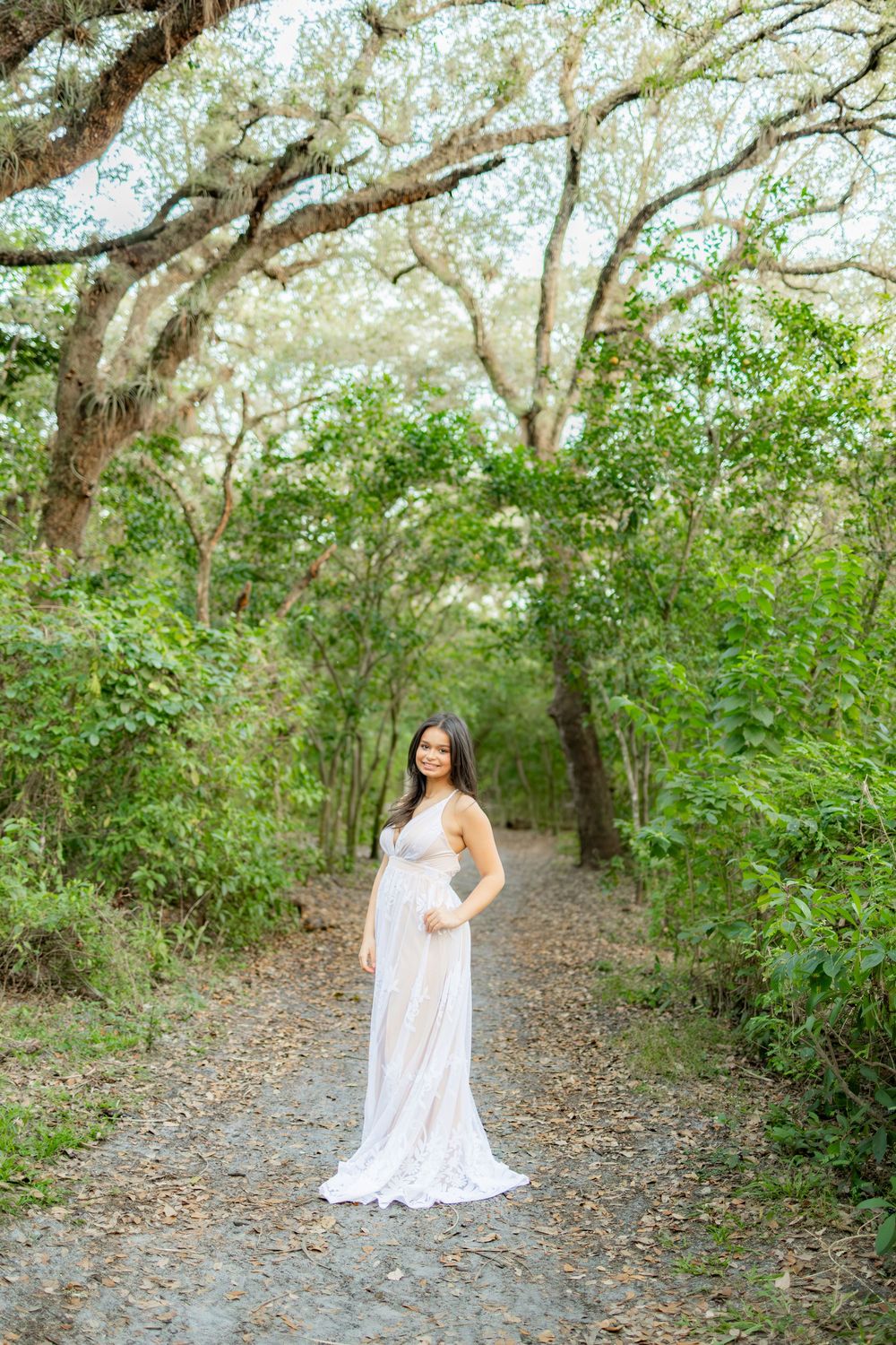 senior portrait with lace dress and tall trees at tree tops park in davie
