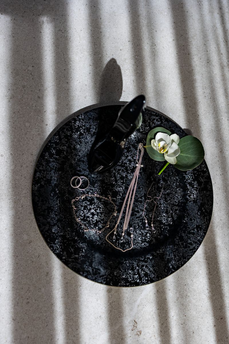 Black velvet hat display with delicate white orchid decorations and wedding rings.