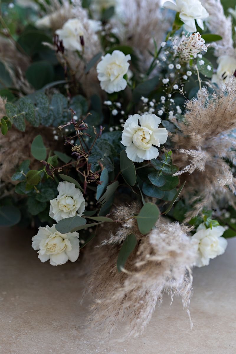 White floral arrangement with pampas grass and eucalyptus creating a soft, romantic centerpiece.