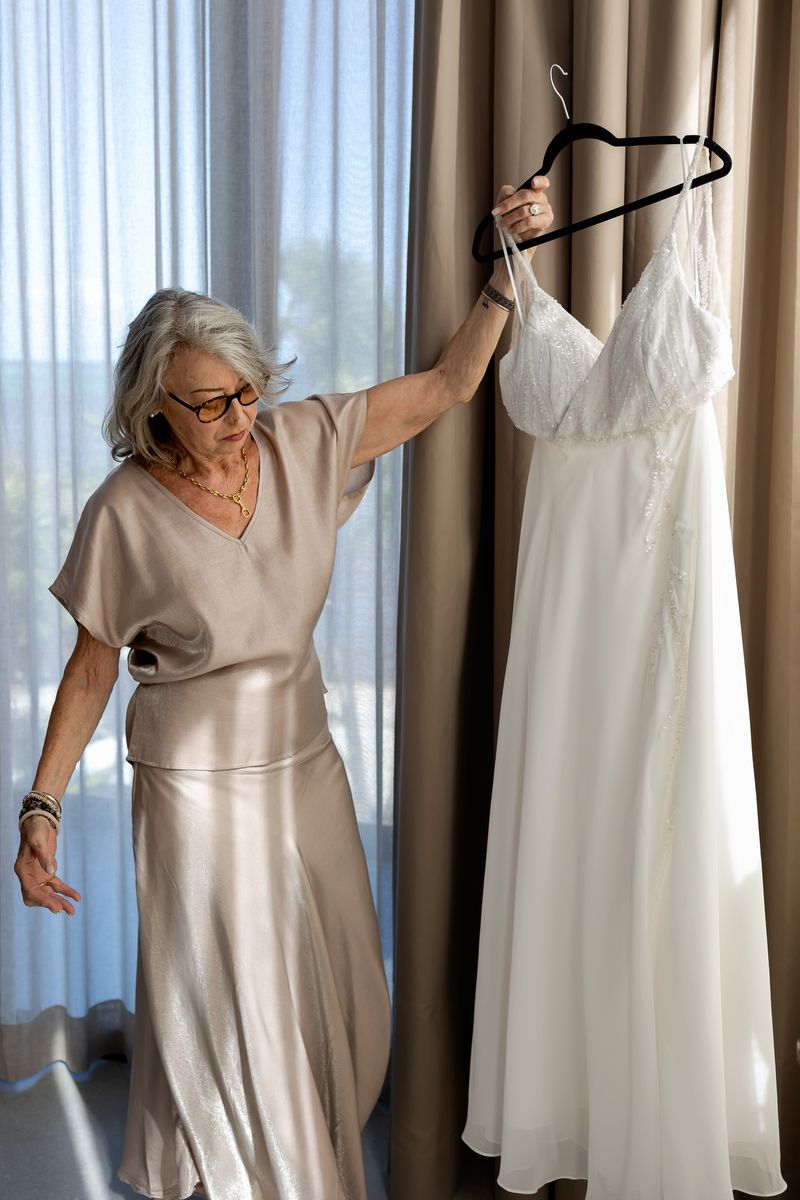 Bride’s mother holding wedding dress in soft natural light during getting ready at Tulum beach wedding.