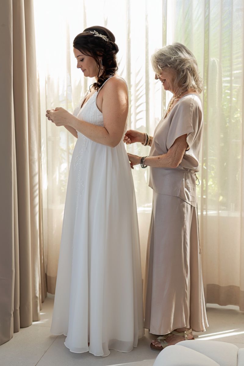 Bride getting dressed with her mother in intimate getting ready moment at Tulum destination wedding.