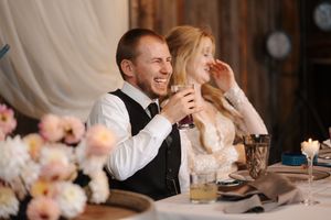 A happy couple shares a joyful moment during their wedding reception at an elegant indoor venue.