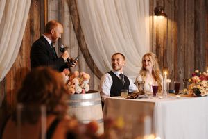 Elegant wedding reception venue with white drapes and crystal chandeliers creating a romantic ambiance during dinner.