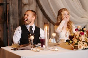 Candid moments of laughter and joy shared during wedding reception speeches at rustic barn venue.