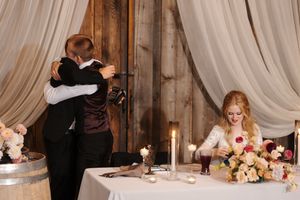 A wedding couple dances in an elegant ballroom with white drapes and romantic lighting during their first dance.
